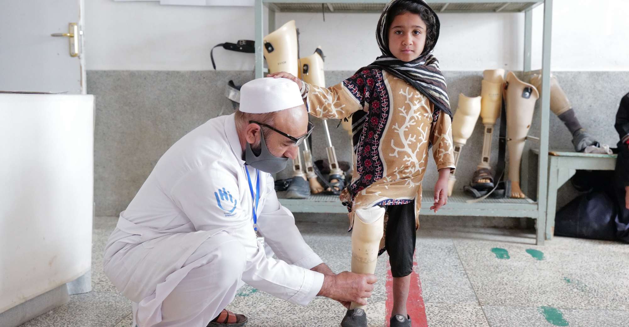 Ein kleines Mädchen bekommt ihre Bein-Prothese von einem Experten von Handicap International angepasst.